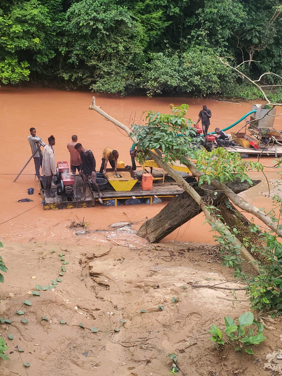 Artisanal mining crew working a river site with pumps and sluice equipment