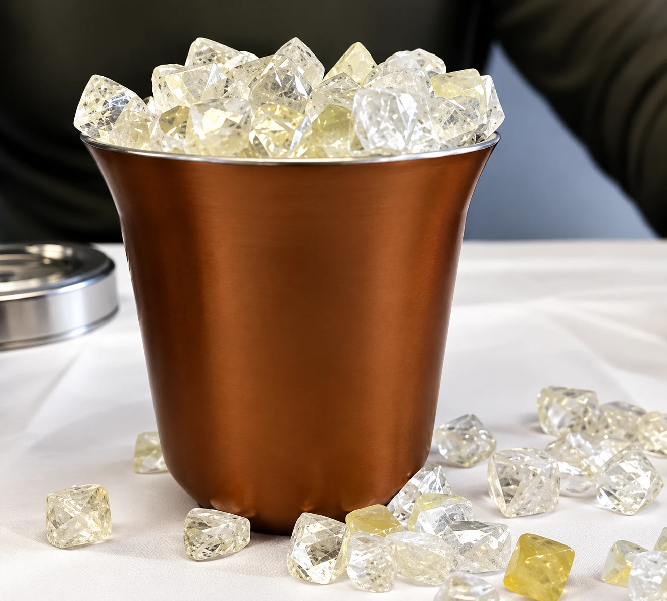 Clear and pale yellow faceted mineral samples in a copper-coloured container